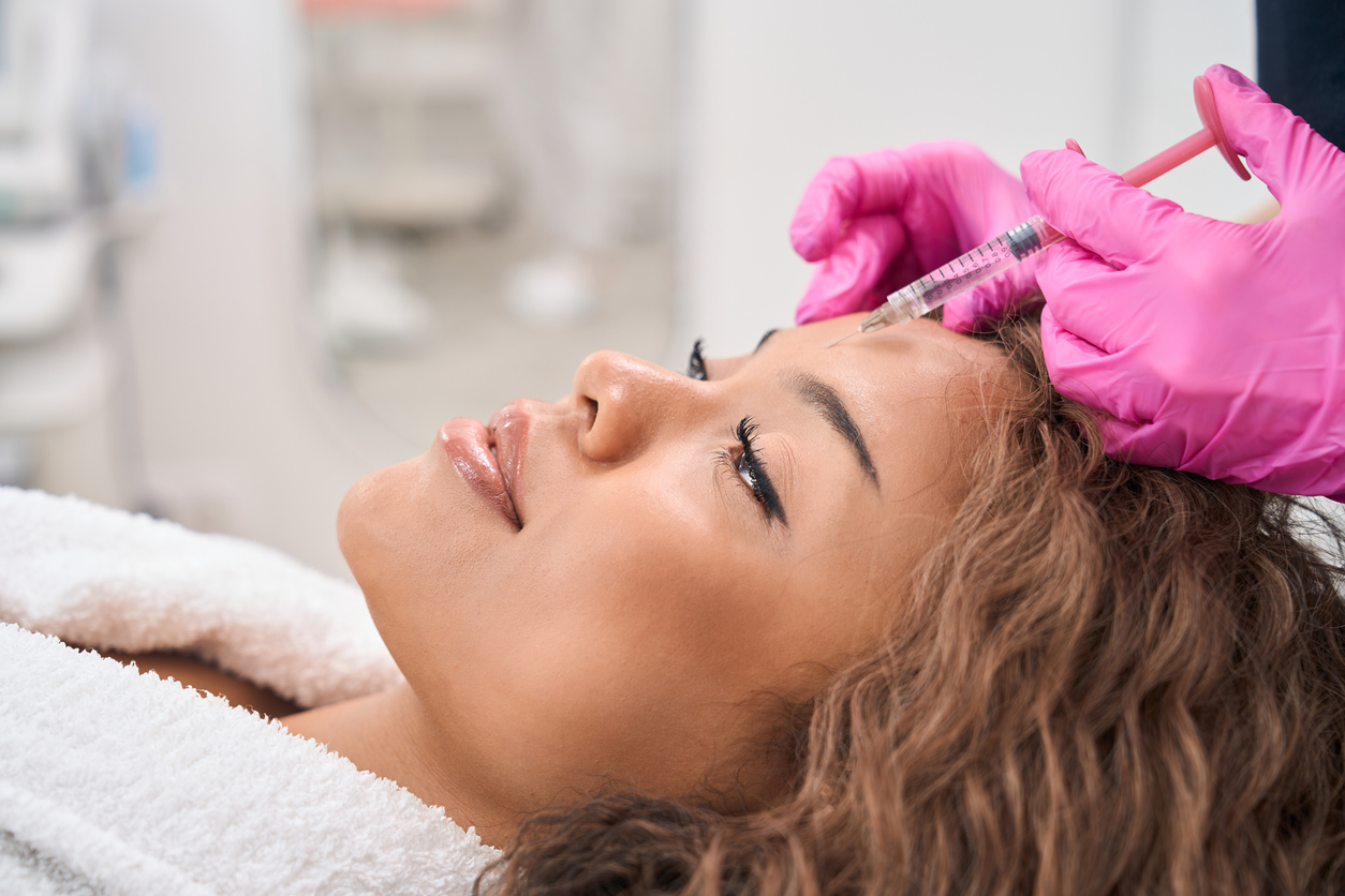 An aesthetician injects a repeat aesthetic patient with Botox, representing a med spa loyalty program