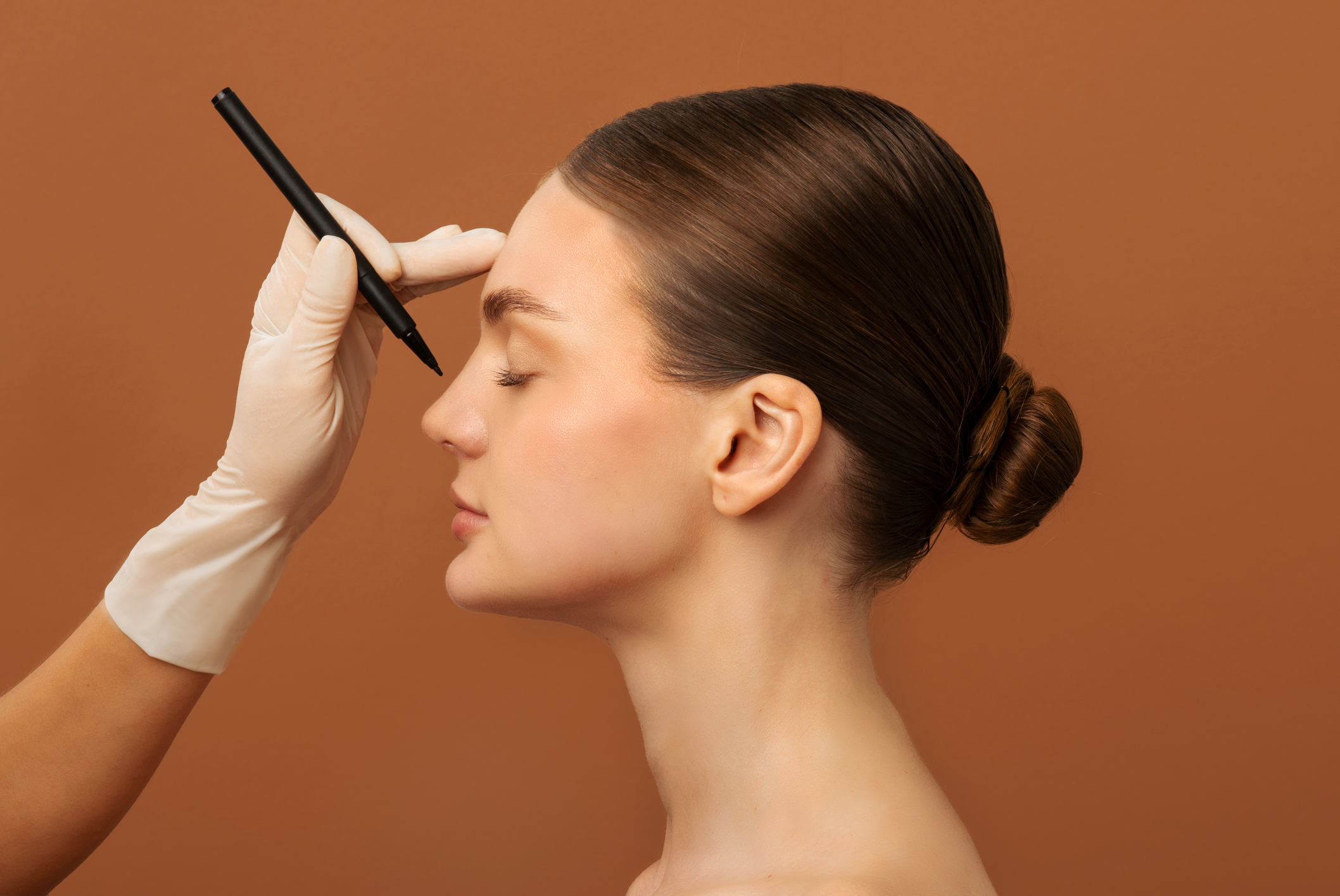 Side profile of a model with a plastic surgeon’s pen poised above her nose, representing plastic surgery industry trends.